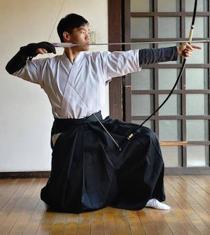 Philip at full draw in kyudo gear.